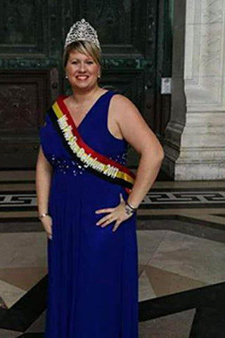 Une femme couronnée porte une écharpe "Miss Plus Size Belgium 2017" et une robe bleue élégante.