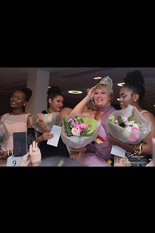 Un groupe de femmes élégantes, lauréates, couronnées et souriantes, tenant des bouquets lors d'une cérémonie.