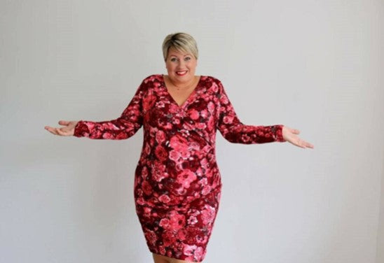 femme ronde souriante dans robe à fleurs roses et rouges