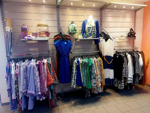 Ma Petite Folie, magasin de vêtements expose des robes colorées, accessoires et tenues élégantes sur des étagères éclairées.